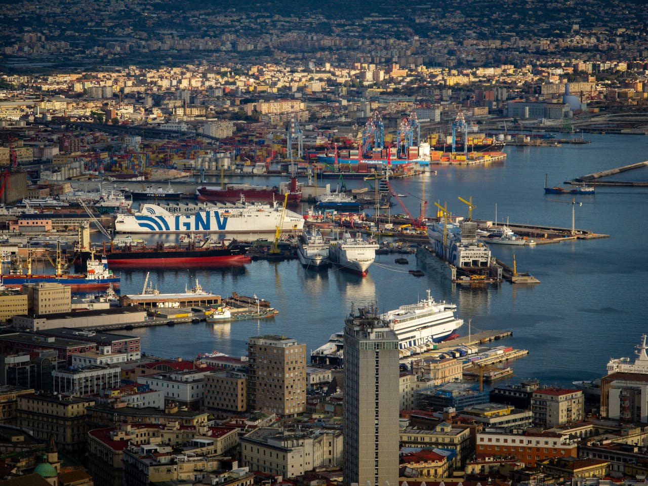 Aerial photograph showcasing a bustling port with ships and cityscape in Naples, Italy.